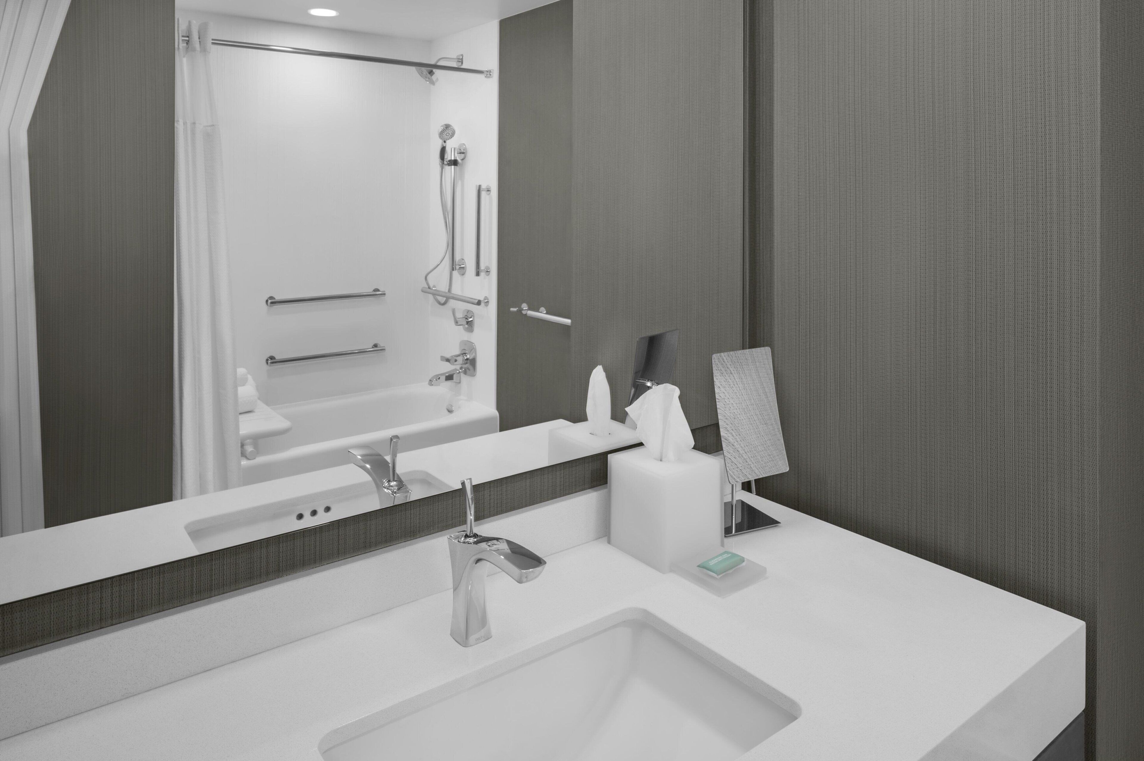 A modern bathroom with a large mirror, a sink, and a shower area.