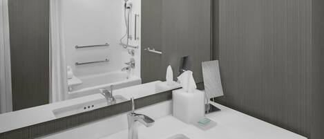 A modern bathroom with a large mirror, a sink, and a shower area.