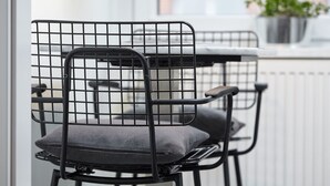 A modern chair with a metal frame and a cushioned seat, positioned near a window with a view of a building and a potted plant. - Strandpirat - Holiday apartment for two (Sankt Peter-Ording)