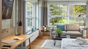 A modern living room with a sofa, a desk, and a TV. - Strandpirat - Holiday apartment for two (Sankt Peter-Ording)