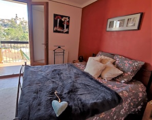 Une chambre à coucher avec un lit, une vue sur l’extérieur et un mur rouge.