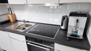A modern kitchen with a stainless steel sink, a coffee machine, and a built-in oven.