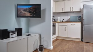 Une cuisine moderne avec des meubles blancs, un four à micro-ondes et un réfrigérateur en acier inoxydable.