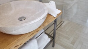 Ett stort, runt handfat i marmor placerat på en träbänkskiva i ett badrum med ett kaklat golv.