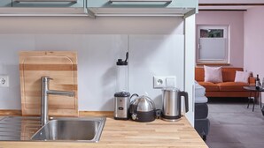 A modern kitchen with a stainless steel sink, wooden cutting board, blender, kettle, and coffee maker. - Oystercatcher - Holiday cottage for two (St Peter Ording)