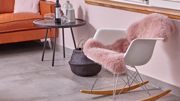 A modern living room with a rocking chair, a sofa, a small table with a wine bottle, and a basket. - Oystercatcher - Holiday cottage for two (St Peter Ording)