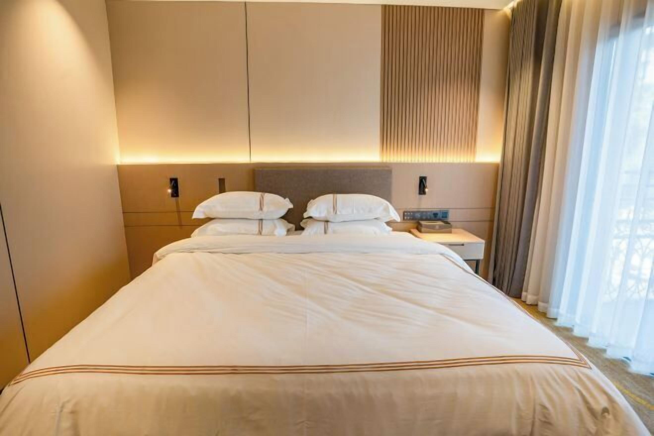 A hotel room with a large bed, a bedside table, and a nightstand.