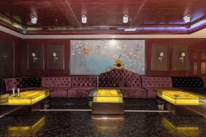 A lobby with a dark wood ceiling, a large abstract painting, and a plush purple sofa with matching armchairs. - Jingyang Hotel (Yingshan)