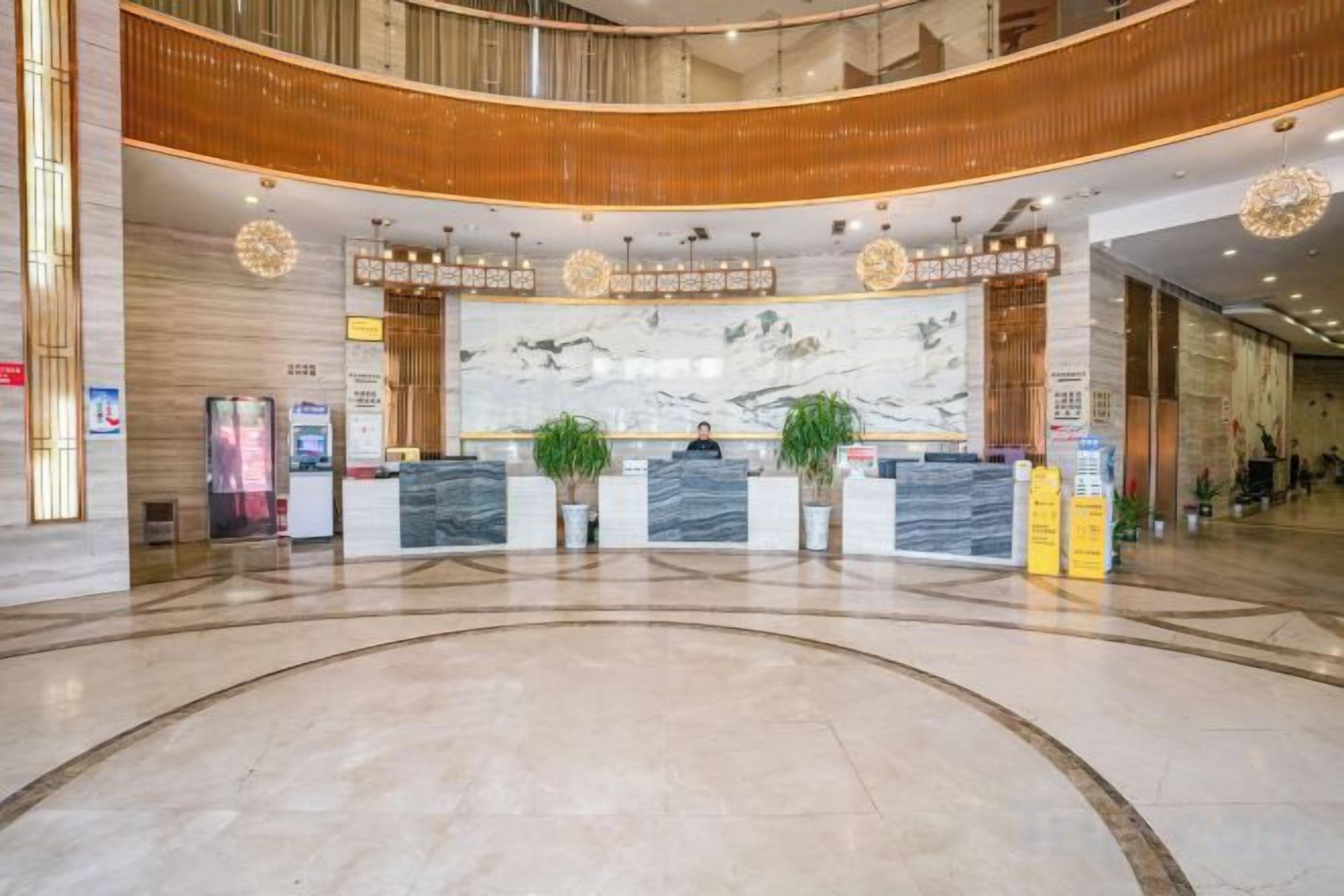 A hotel lobby with a reception desk, a large marble wall, and a curved ceiling.