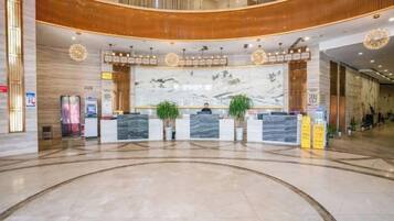 A hotel lobby with a reception desk, a large marble wall, and a curved ceiling.