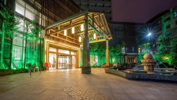 A hotel entrance with a covered walkway, a stone pathway, and a water feature. - Jingyang Hotel (Yingshan)
