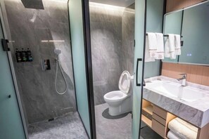 A modern bathroom with a glass-enclosed shower, a toilet, and a vanity with a mirror and sink. - Jingyang Hotel (Yingshan)