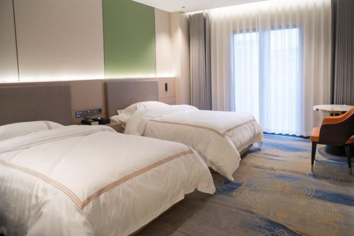 A hotel room with two beds, a desk, and a chair.