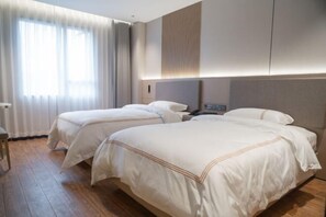 A hotel room with two beds, wooden flooring, a large window with curtains, and a modern headboard. - Jingyang Hotel (Yingshan)