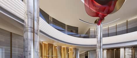 A spacious lobby with a high ceiling, marble columns, and a central seating area.