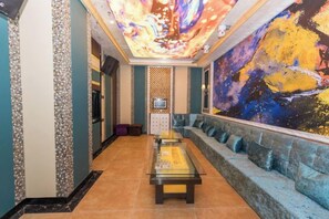 A hotel lobby with a central coffee table, seating area, and a large abstract painting on the wall. - Jingyang Hotel (Yingshan)