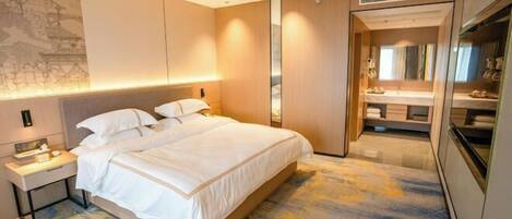 A hotel room with a bed, bedside table, and a bathroom with a mirror and sink.