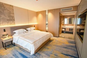 A hotel room with a bed, bedside table, and a bathroom with a mirror and sink. - Jingyang Hotel (Yingshan)