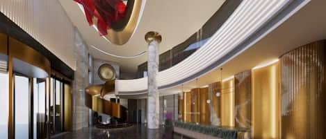 A spacious lobby with a central staircase, a large chandelier, and a seating area.