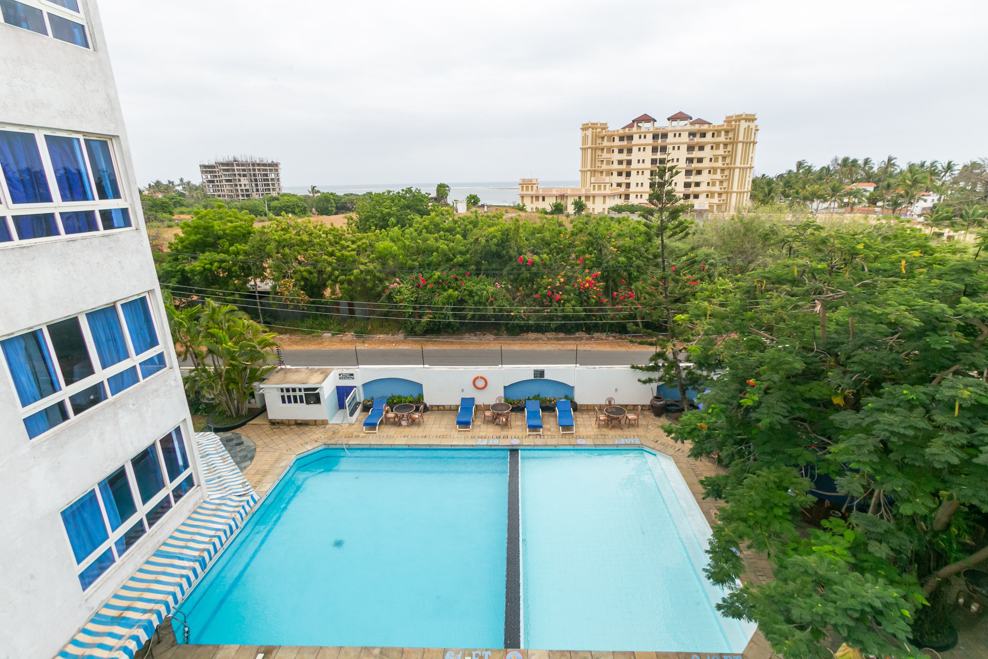 Una piscina con sillas de descanso y vista a un edificio grande al fondo.