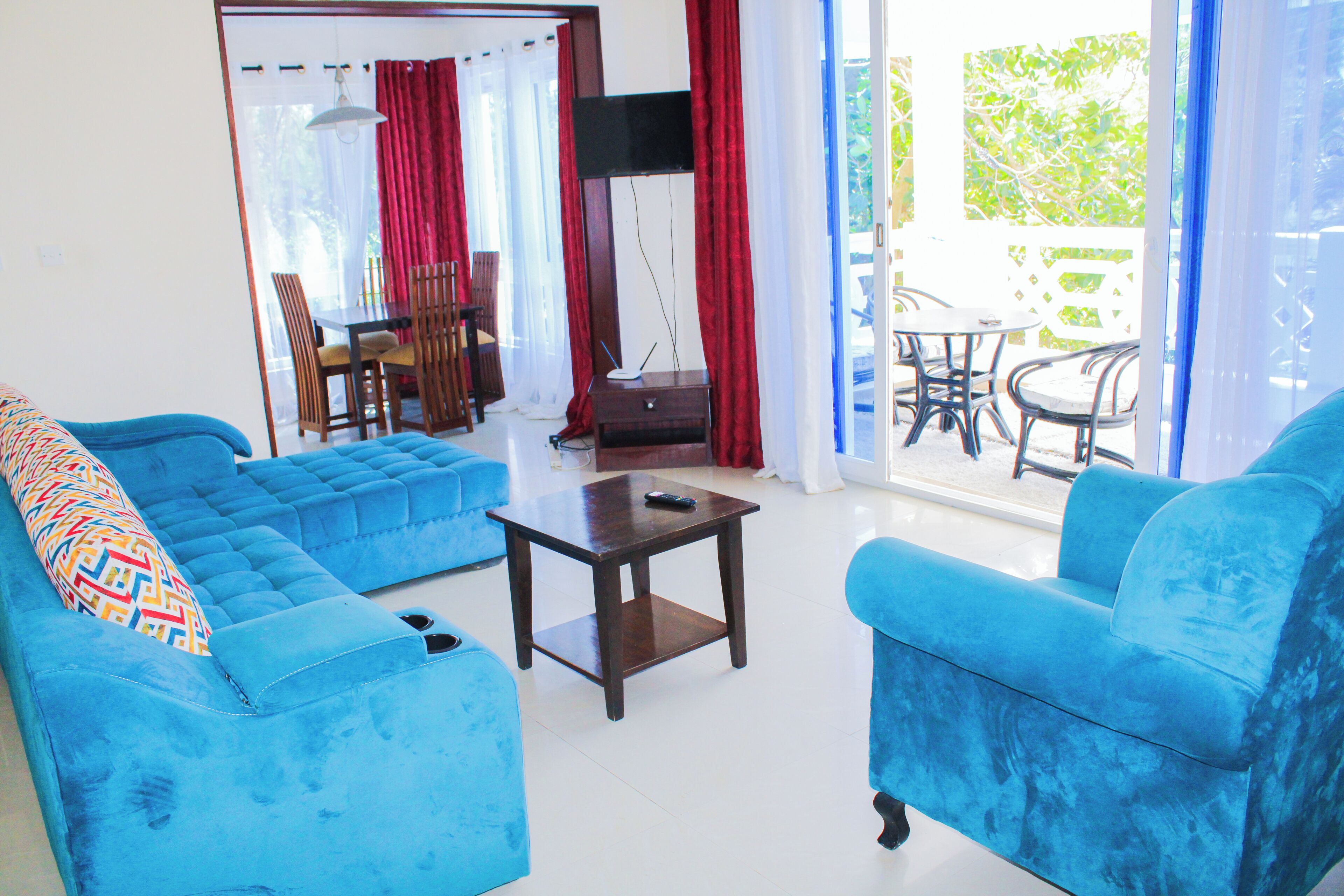 Una sala de estar con dos sofás azules, una mesita y un comedor con sillas y una mesa.