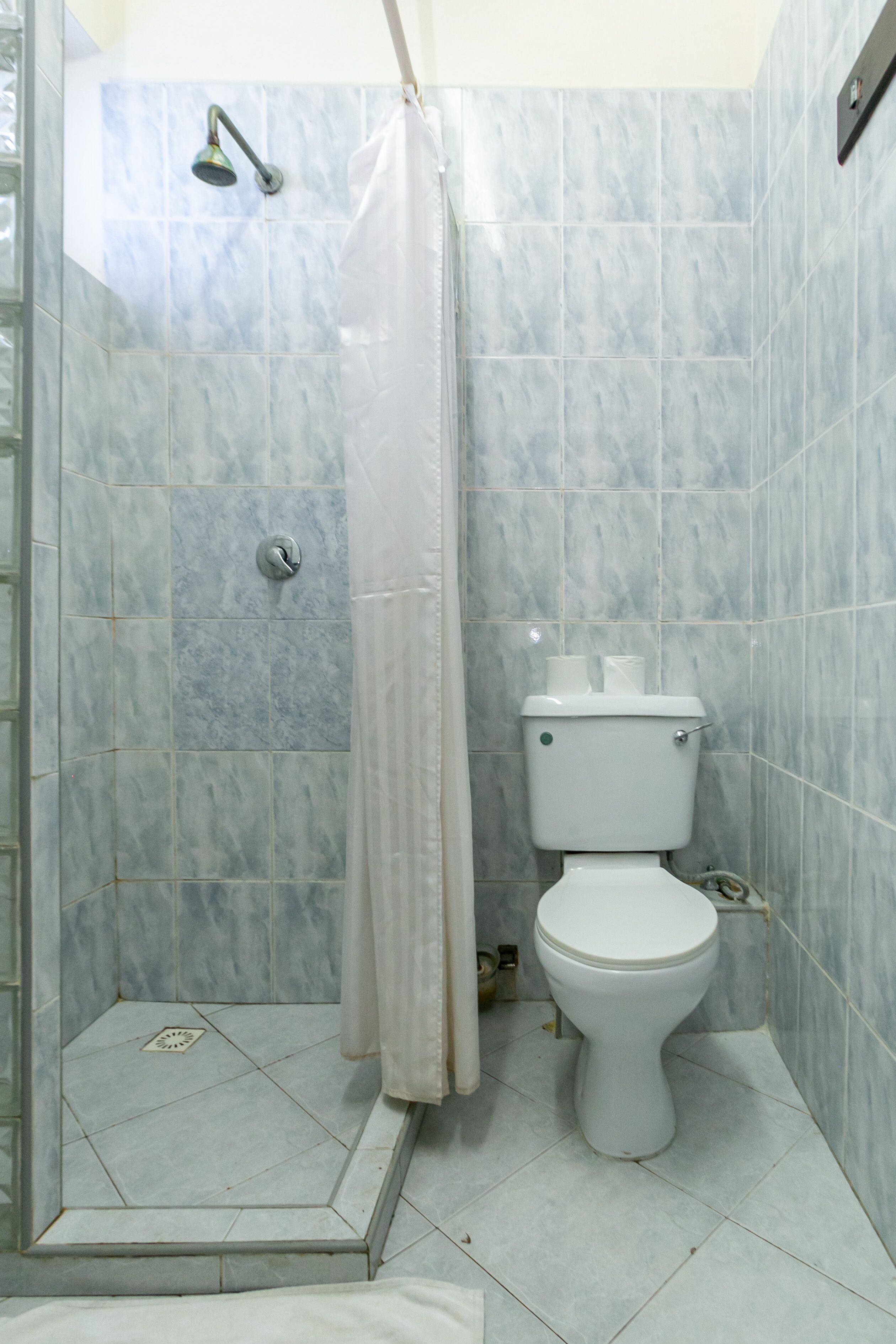 Ein Badezimmer mit Dusche, Toilette und gefliesten Wänden.