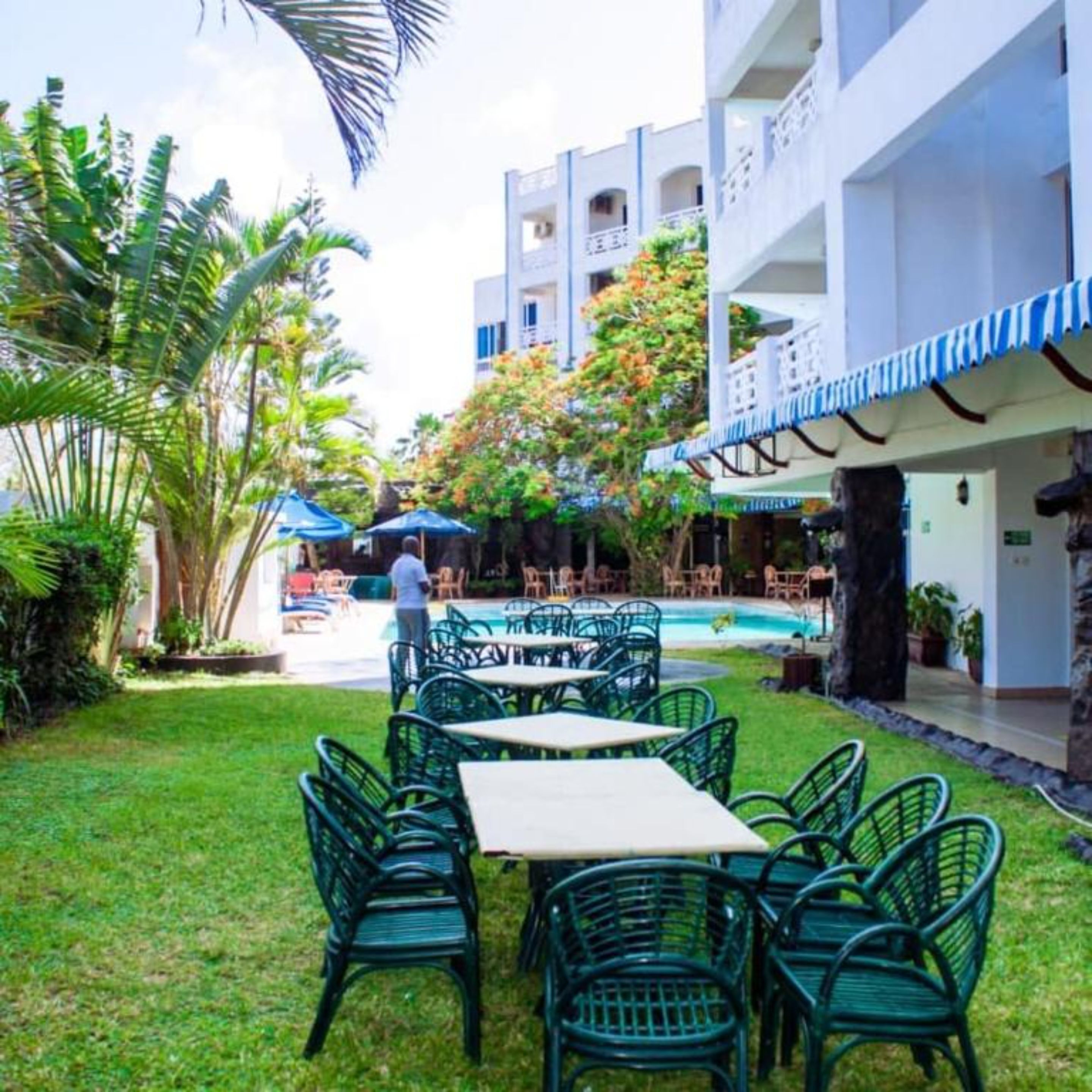 Ein Innenhof mit Außenbestuhlung, einem Pool und einem Gebäude mit Balkonen.