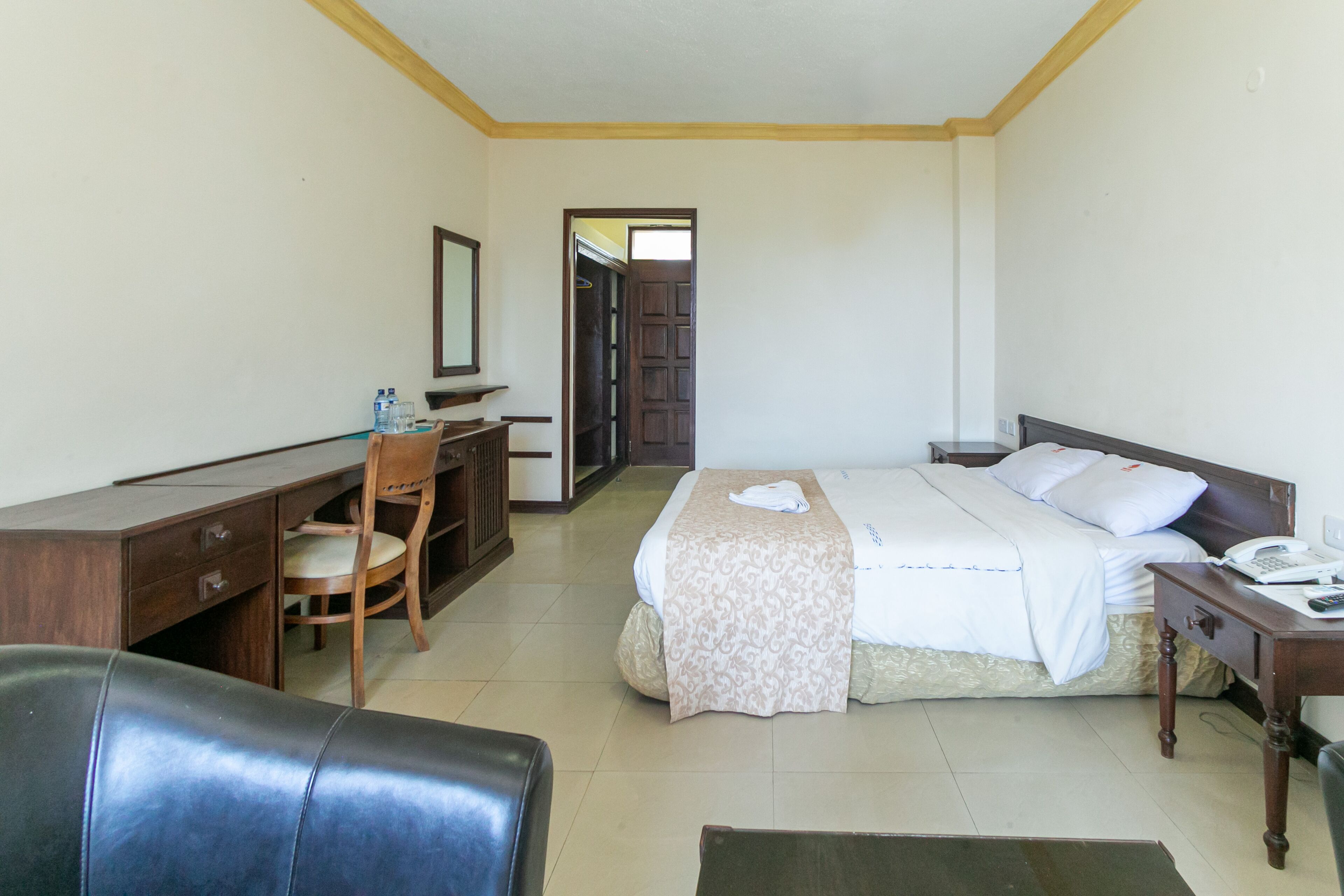 A hotel room with a bed, desk, chair, and a door leading to another room.