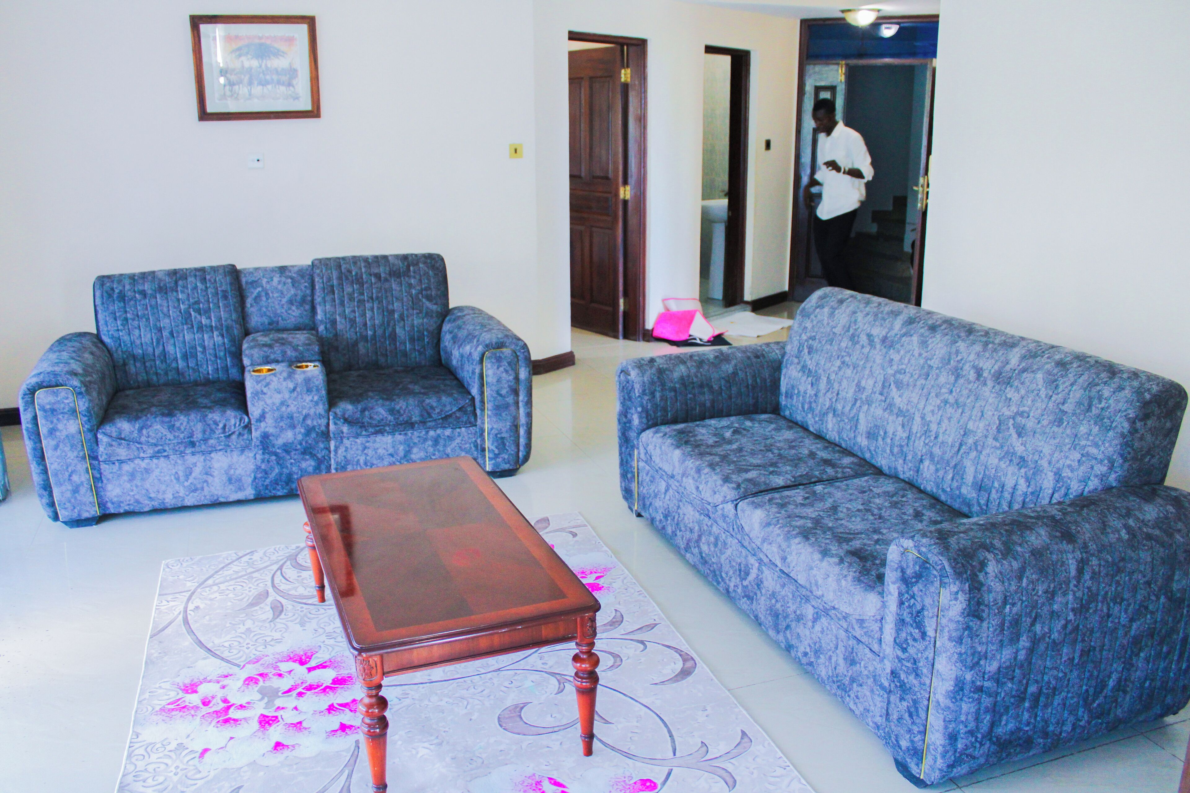 A living room with two blue sofas, a wooden coffee table, and a patterned rug.