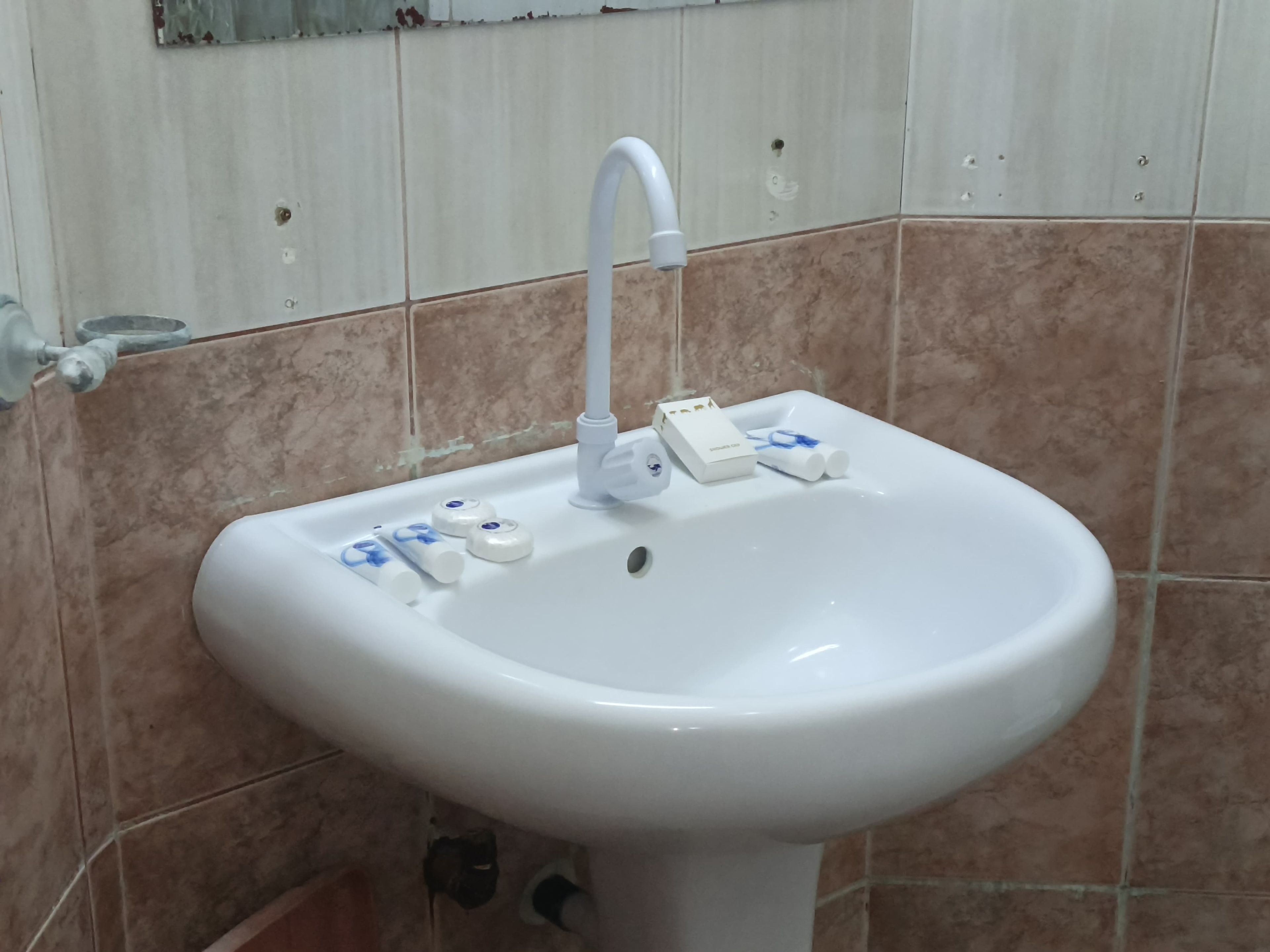A white bathroom sink with a faucet, a soap dispenser, and a toothbrush holder.