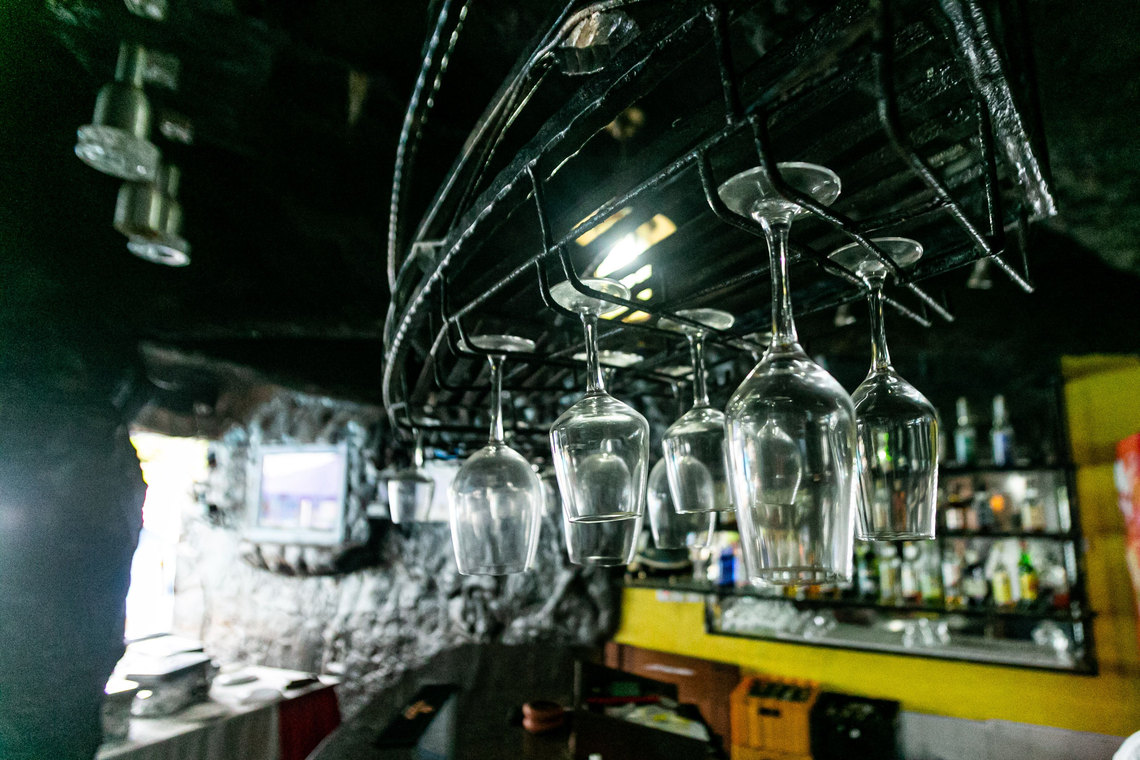 Zona de bar con copas de vino colgantes y una pantalla de televisión al fondo.