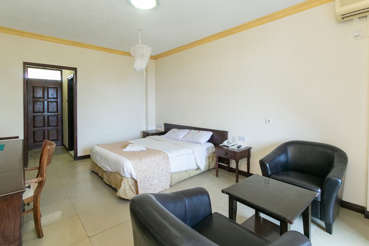 A hotel room with a bed, a desk, a chair, and a table.