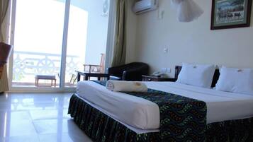 Una habitación de hotel con cama, escritorio, silla, balcón y aire acondicionado.