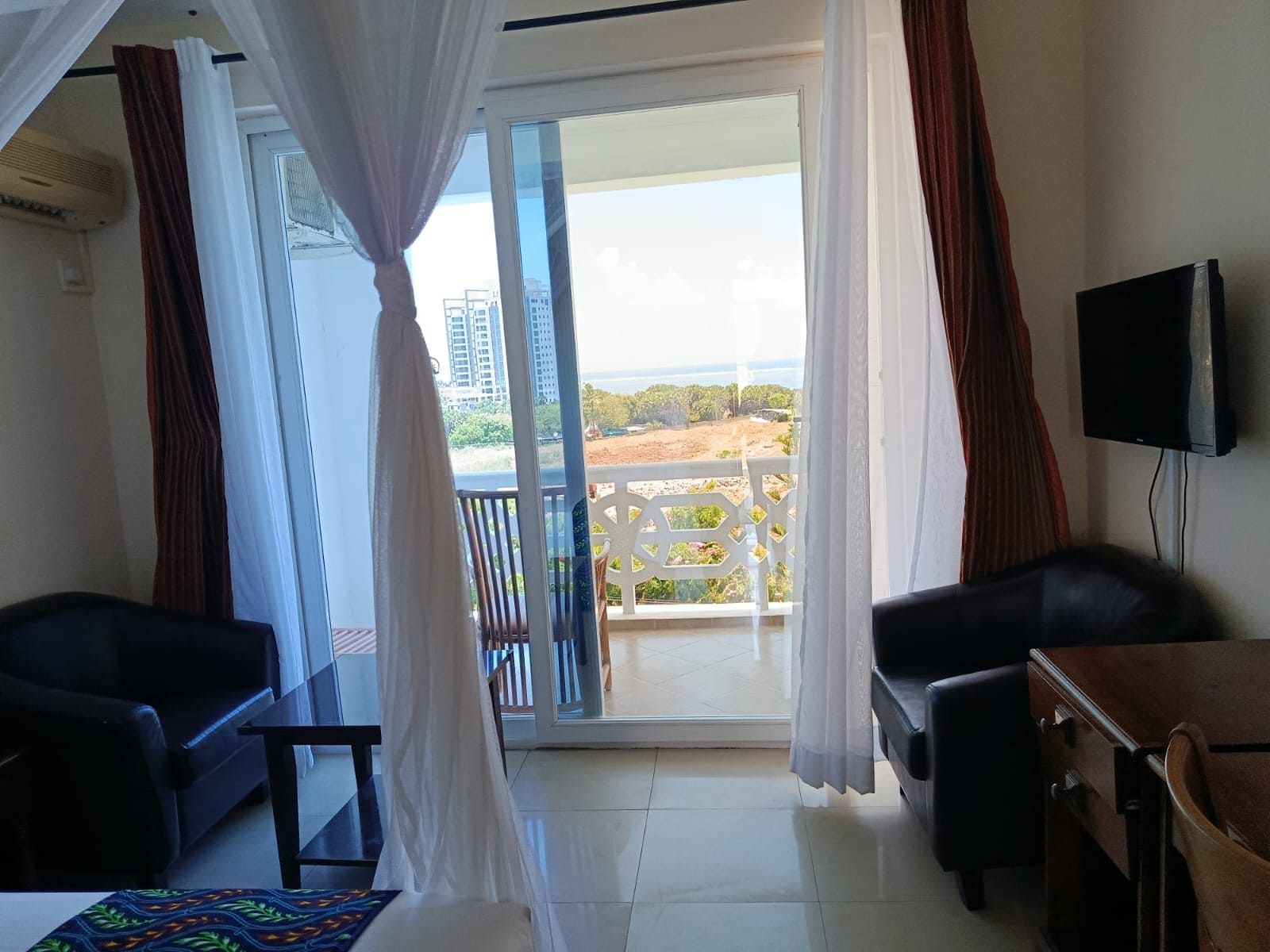 A room with a balcony, a television, and a bed.