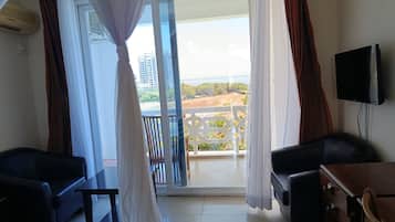 A room with a balcony, a television, and a bed.