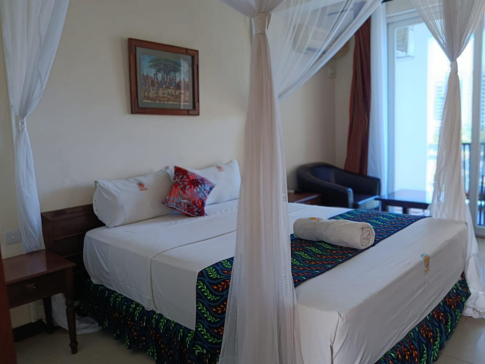 A hotel room with a bed, a desk, a chair, and a window with curtains.