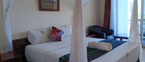 A hotel room with a bed, a desk, a chair, and a window with curtains.