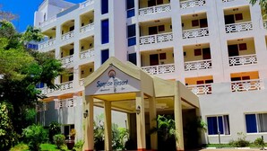 Un hotel de varios pisos con balcones, una entrada cubierta y un cartel que dice Sunrise Resort.