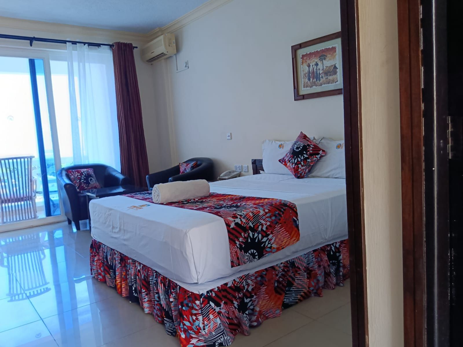 Habitación de hotel con cama, una silla, un sillón de masaje y vistas al exterior.
