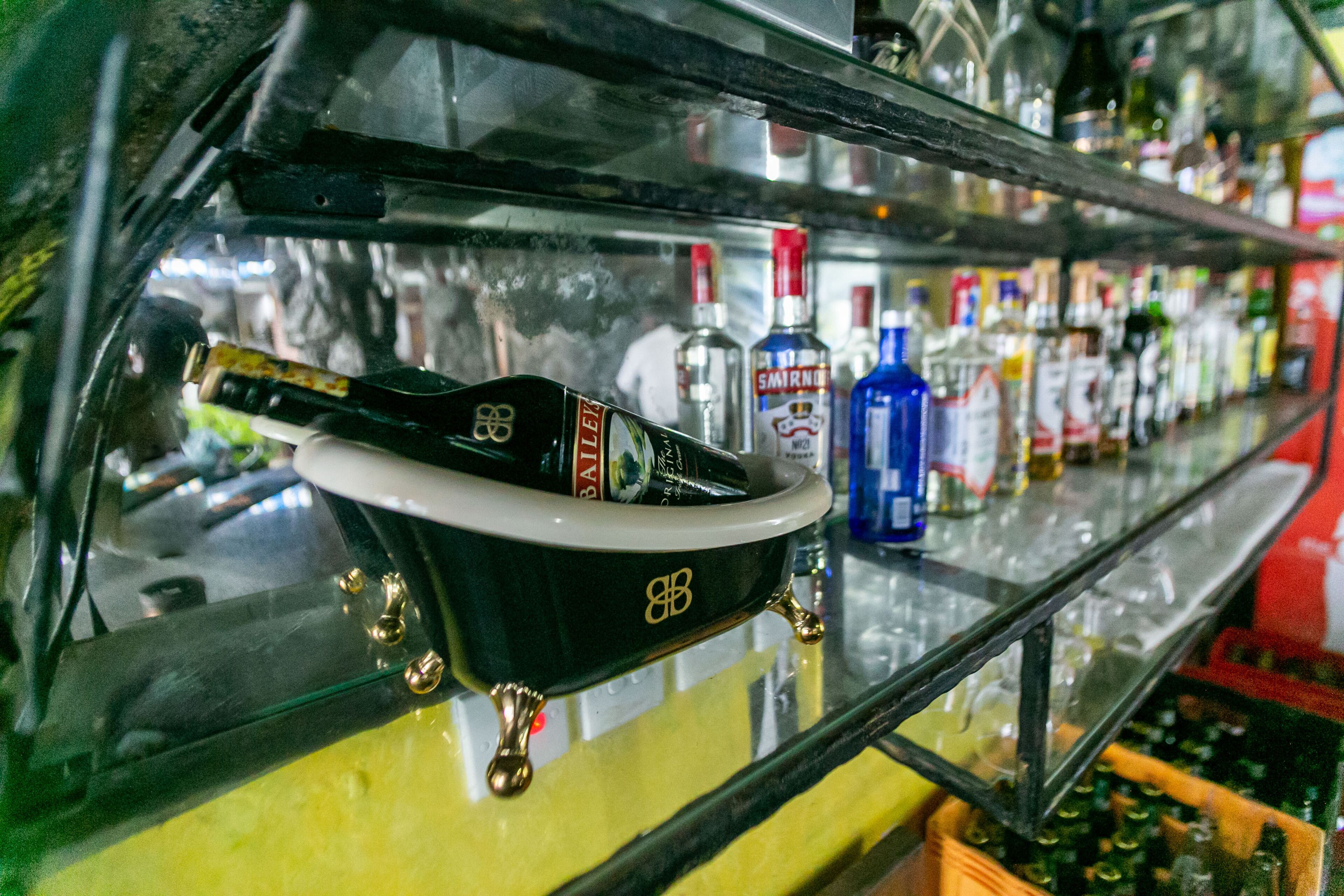 A bar with a black bathtub-shaped container holding a bottle of Baileys.