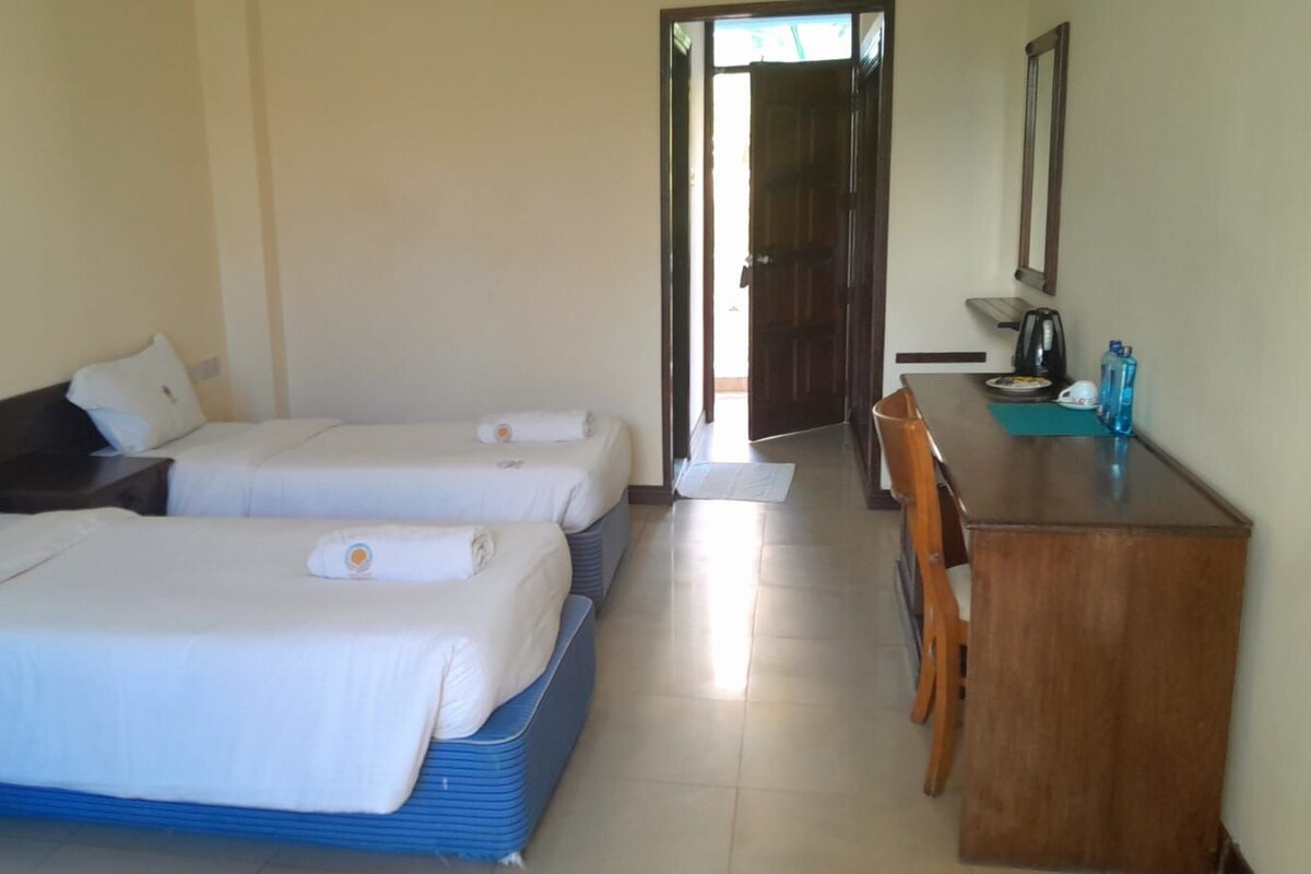A hotel room with two beds, a desk, and a chair.