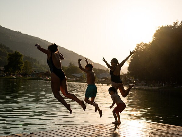 People jumping into water at sunset.