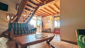 Een houten trap, een bank, een houten tafel en een stoel in een kamer met een betegelde vloer.
