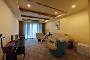 A living room with a sofa, armchairs, a coffee table, and a desk with a lamp. - RGHCM Garden Resorts (Beijing)