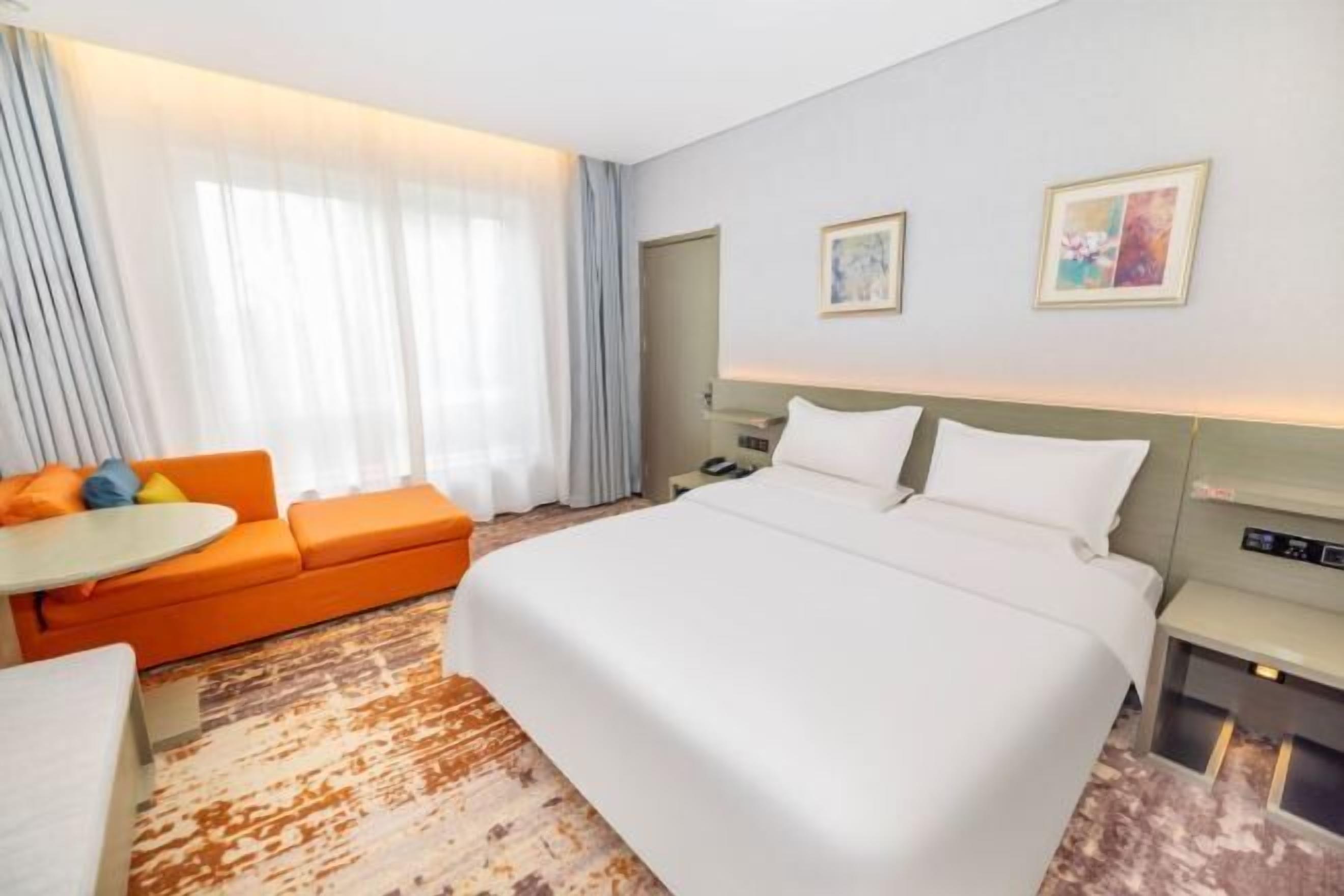 Una habitación de hotel con una cama grande, un sofá, una mesita y un escritorio.