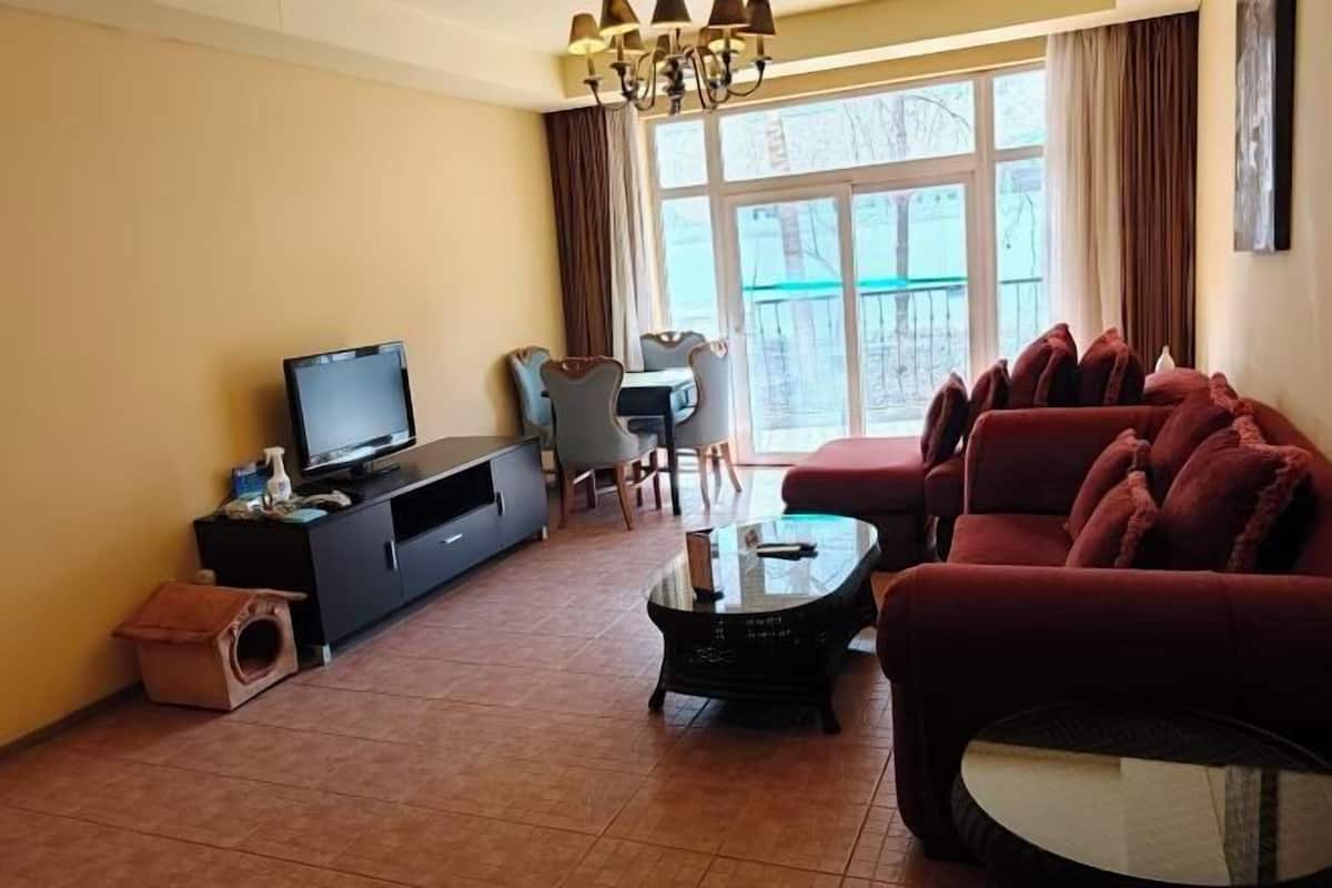 A living room with a sofa, television, and a glass coffee table.