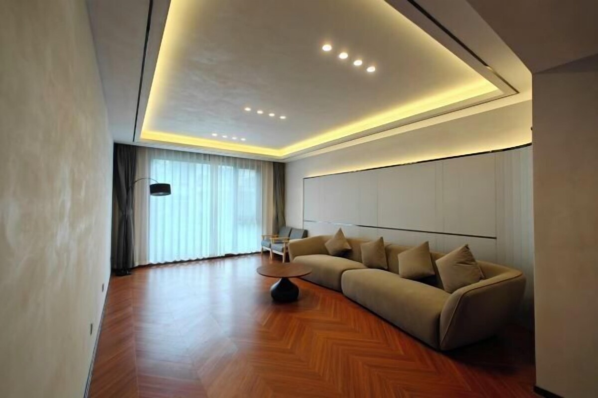 A modern living room with a curved sofa, a round coffee table, and recessed ceiling lighting.