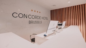 Una recepción de hotel con una pared de mármol que muestra el nombre y la ubicación del hotel.