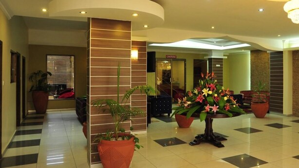 A hotel lobby with a checkered floor, potted plants, a chandelier, and a reception desk. - Nomad Paradise Hotel (Nairobi)