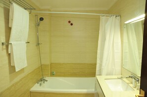 A bathroom with a bathtub, a shower, a sink, and a mirror. - Nomad Paradise Hotel (Nairobi)